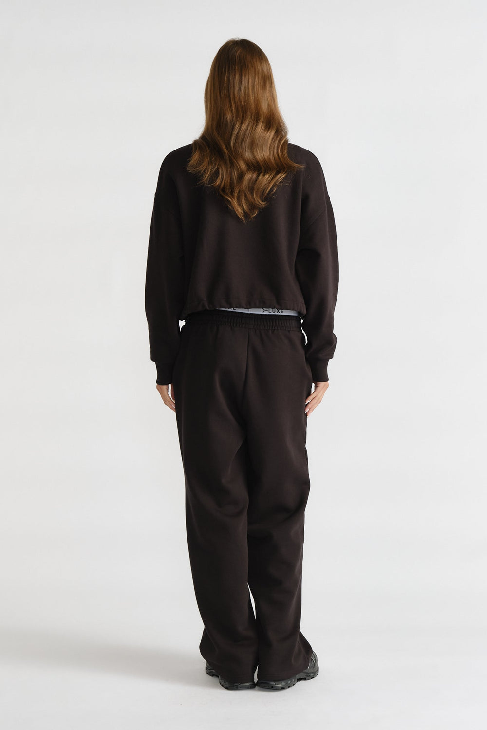 D-Luxe Logo Trackpant in black with a relaxed fit and elastic waistband, styled from the back view by DECJUBA