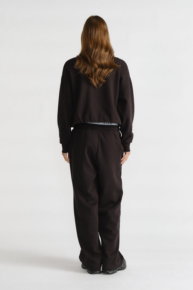 D-Luxe Logo Trackpant in black with a relaxed fit and elastic waistband, styled from the back view by DECJUBA