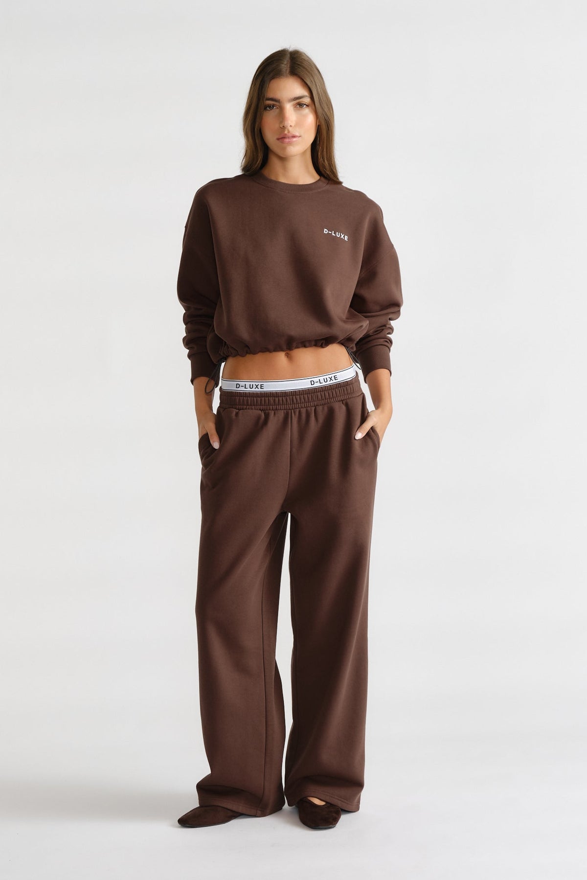 Woman wearing a walnut brown D-Luxe Logo Crop Sweat with relaxed fit pants, styled for effortless everyday comfort.