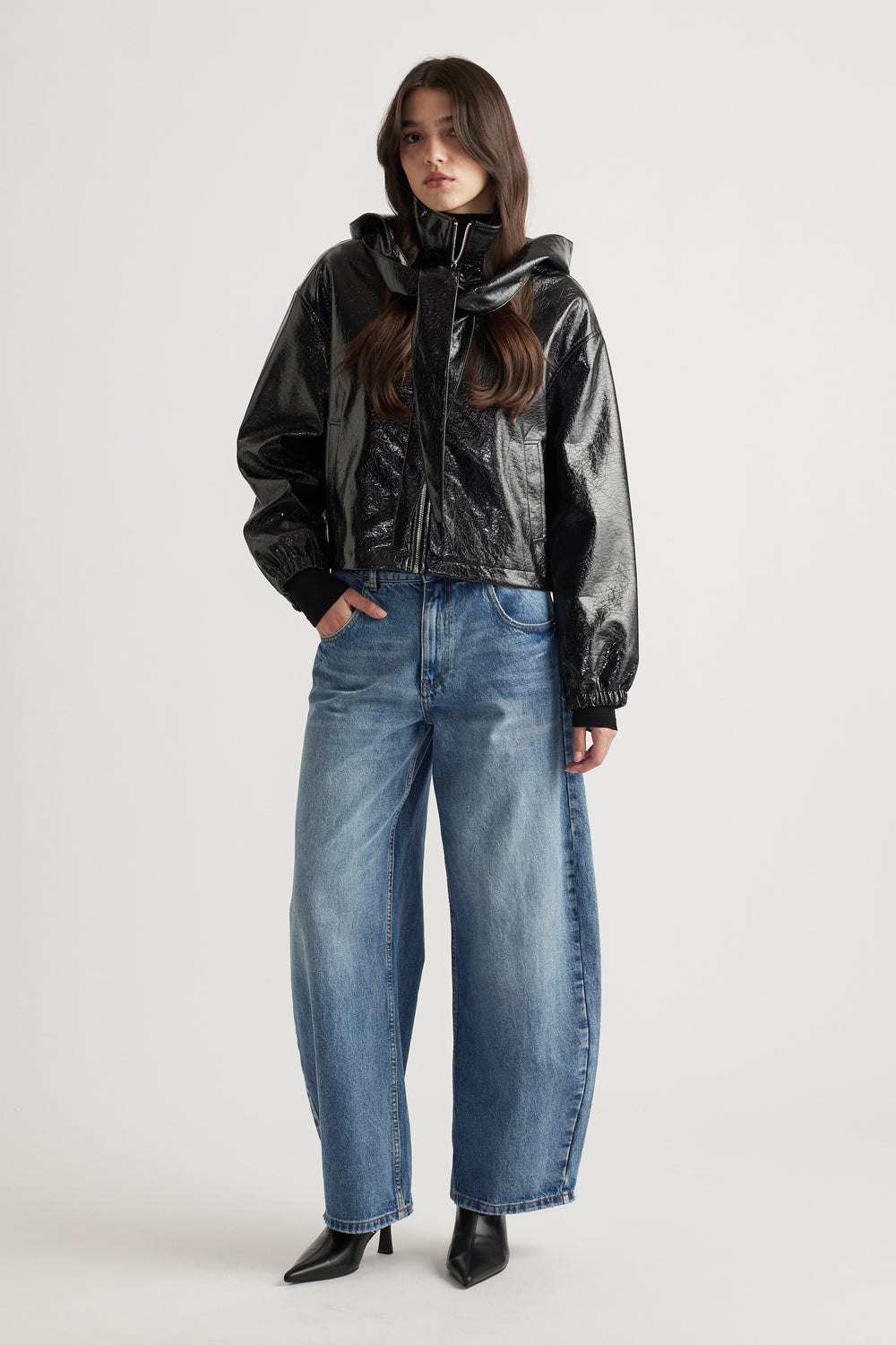 Model wearing a sleek black zip-up jacket styled with relaxed fit blue denim jeans and pointed black ankle boots