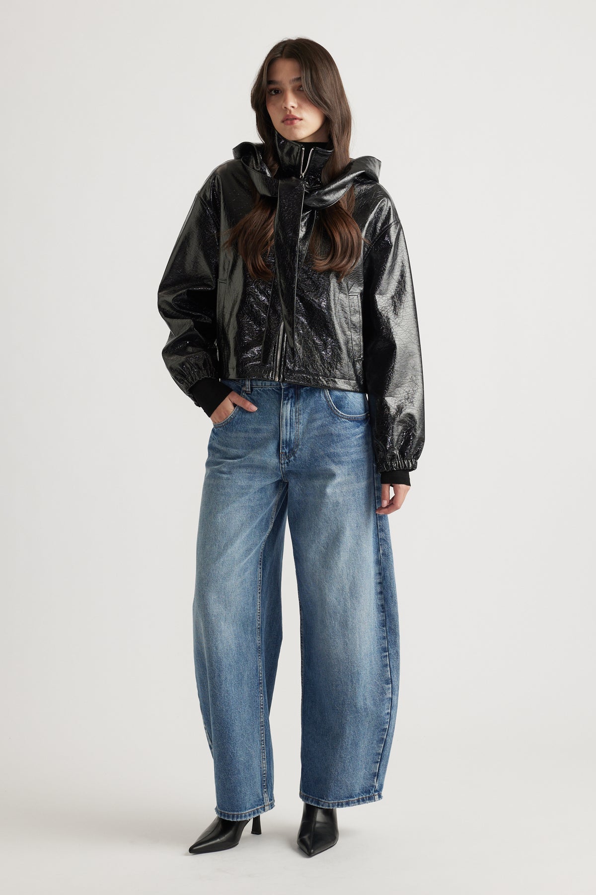 Model wearing a sleek black zip-up jacket styled with relaxed fit blue denim jeans and pointed black ankle boots