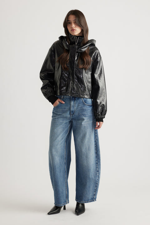 Model wearing a sleek black zip-up jacket styled with relaxed fit blue denim jeans and pointed black ankle boots