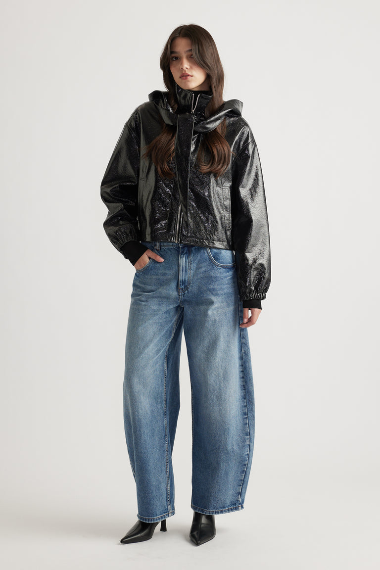 Model wearing a sleek black zip-up jacket styled with relaxed fit blue denim jeans and pointed black ankle boots