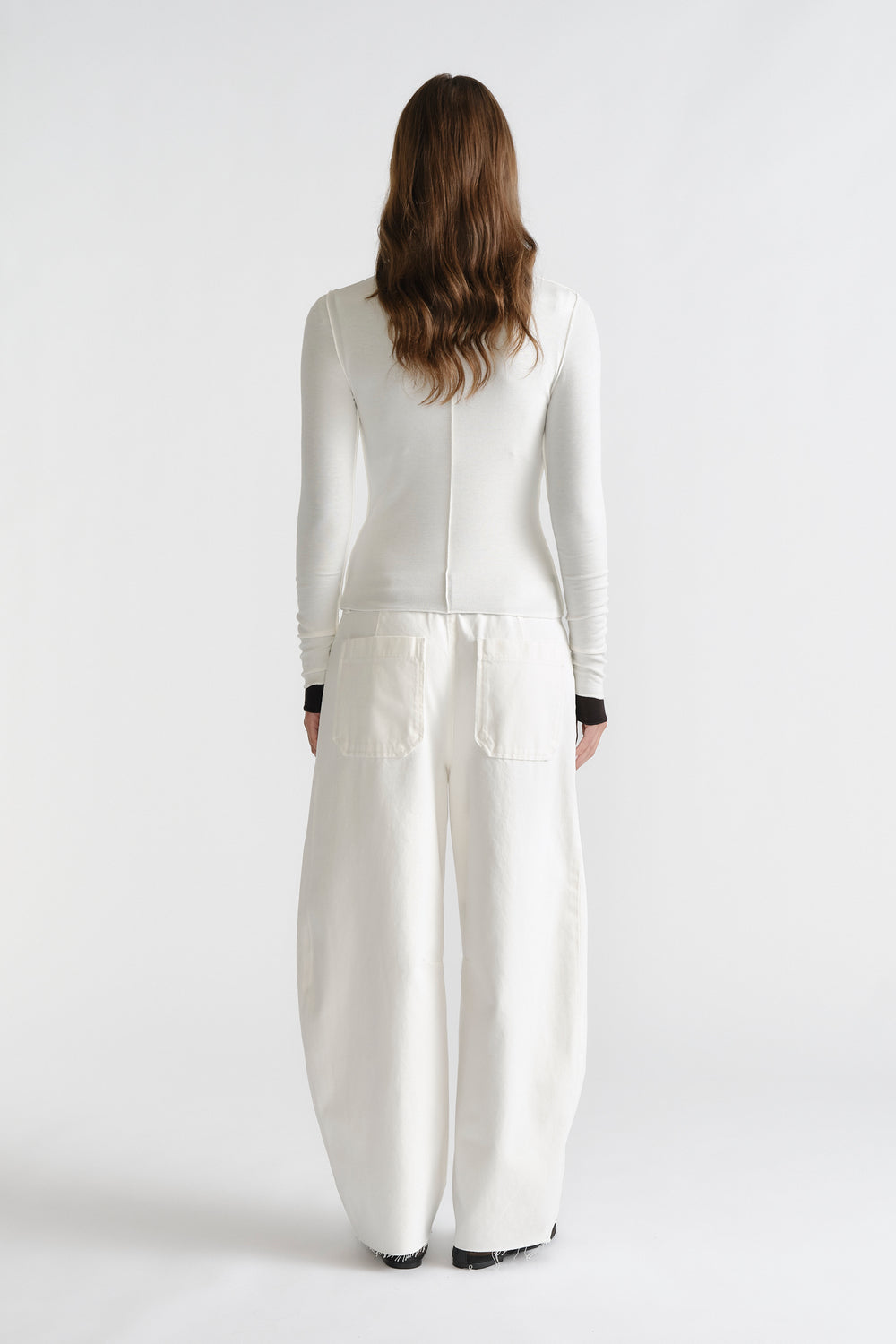D-Luxe Semi Sheer Long Sleeve in soft white with long sleeves and black cuffs, styled with wide-leg white pants by DECJUBA Australian brand