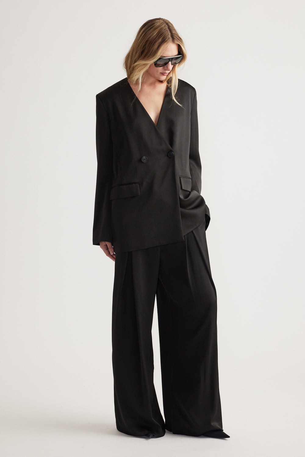 Woman wearing black wide leg pants paired with an oversized double-breasted blazer and sunglasses.