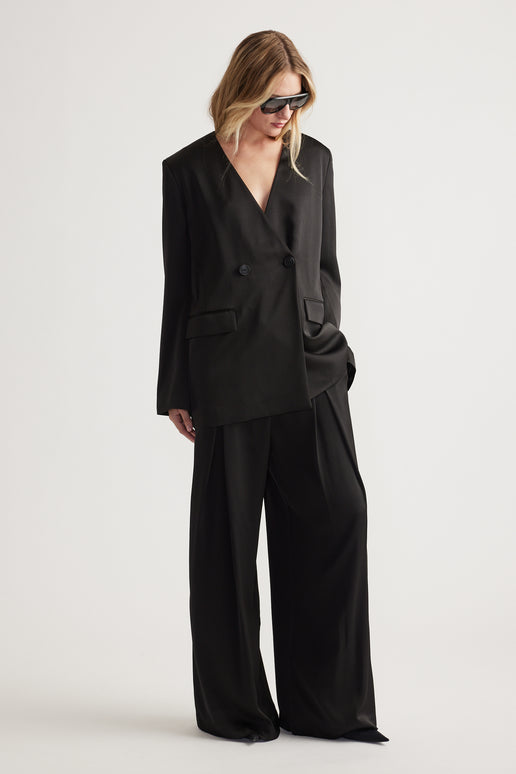 Woman wearing black wide leg pants paired with an oversized double-breasted blazer and sunglasses.