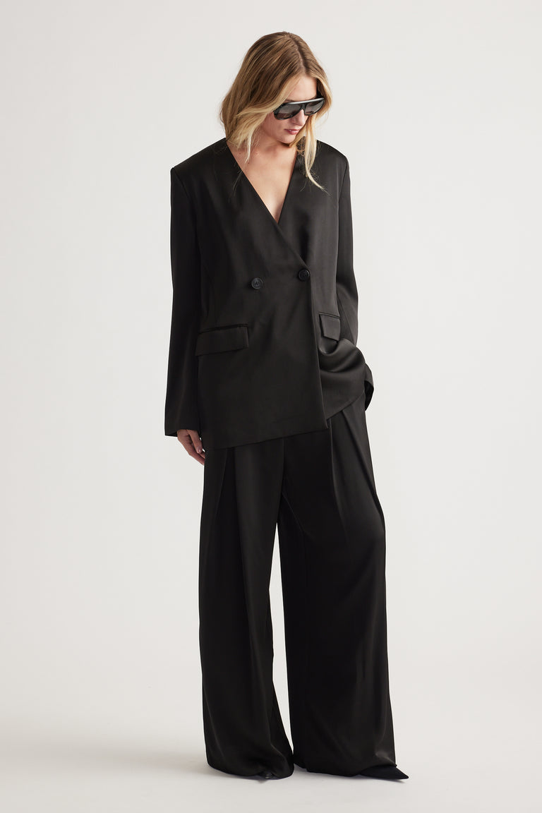Woman wearing black wide leg pants paired with an oversized double-breasted blazer and sunglasses.