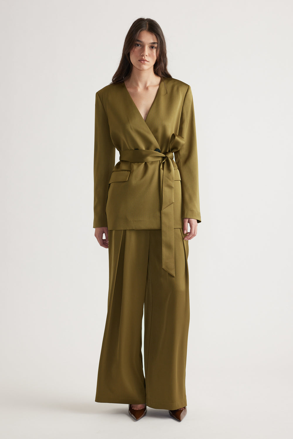Woman wearing an olive green wrap blazer with belt paired with matching wide-leg pants and brown pointed heels