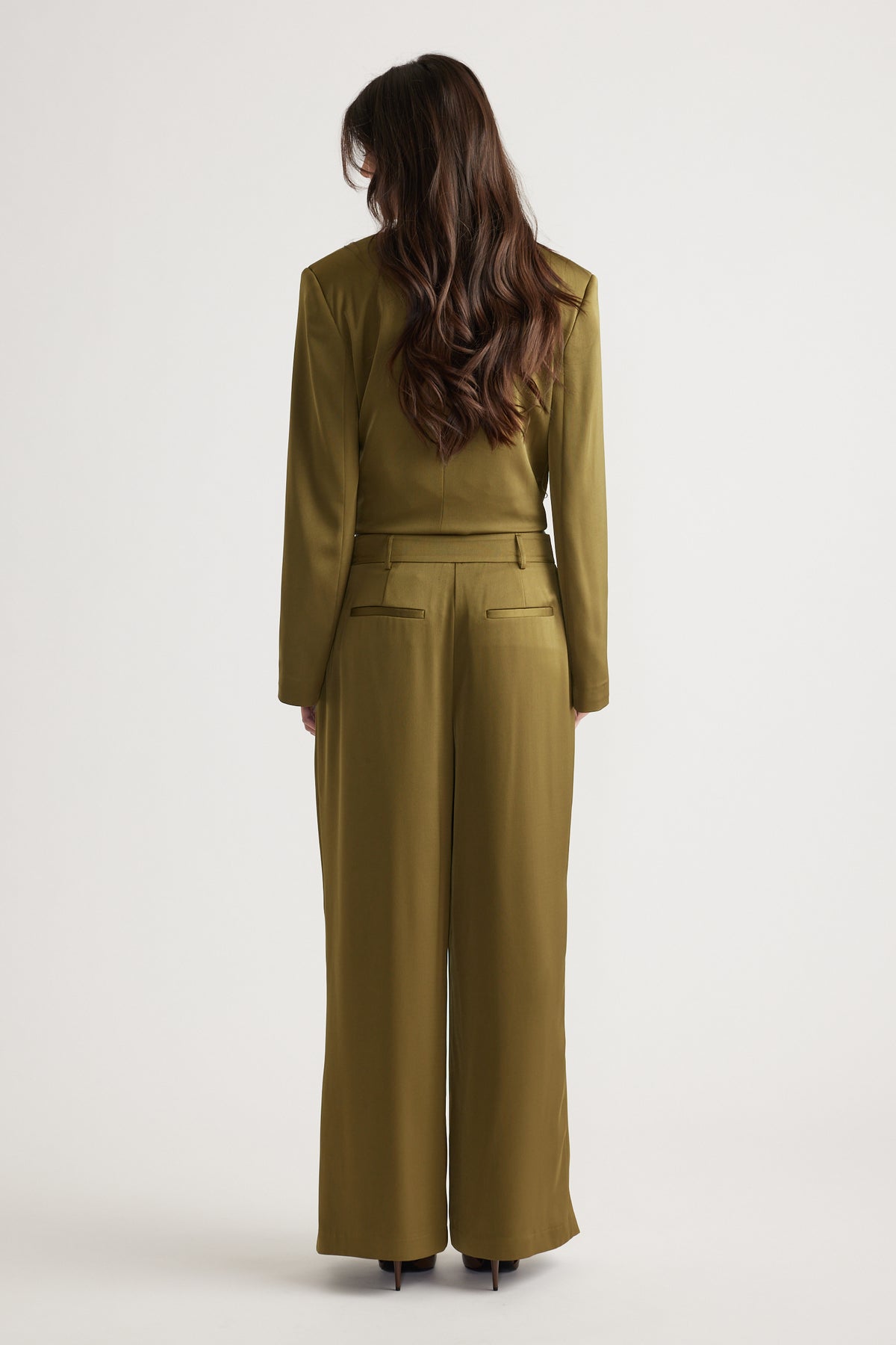 Woman wearing olive wide-leg pants with back pockets paired with a matching fitted jacket and heeled shoes.