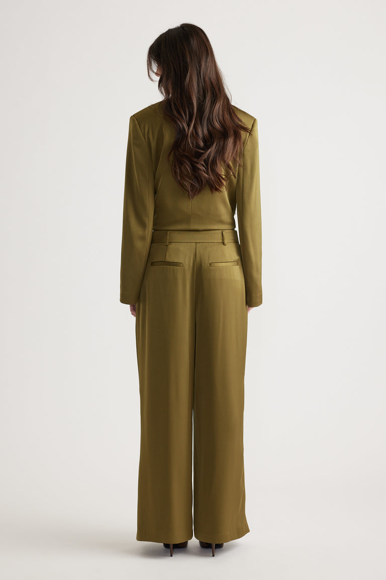 Woman wearing olive wide-leg pants with back pockets paired with a matching fitted jacket and heeled shoes.