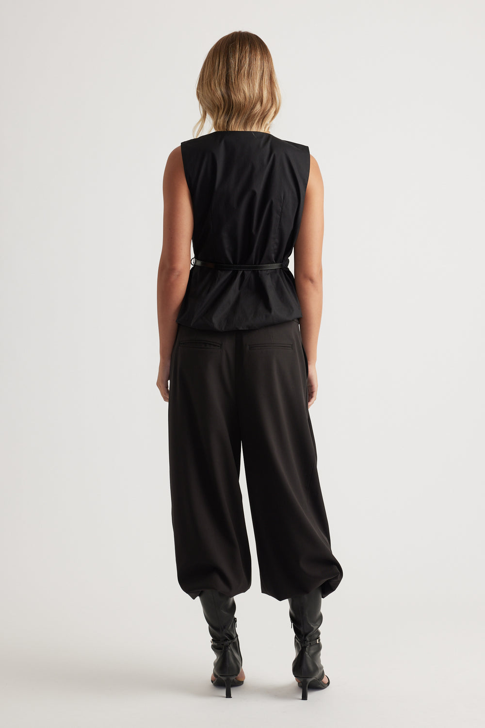 Woman seen from behind wearing Ava Belted Wrap Top in black with sleeveless design and slim belt by DECJUBA