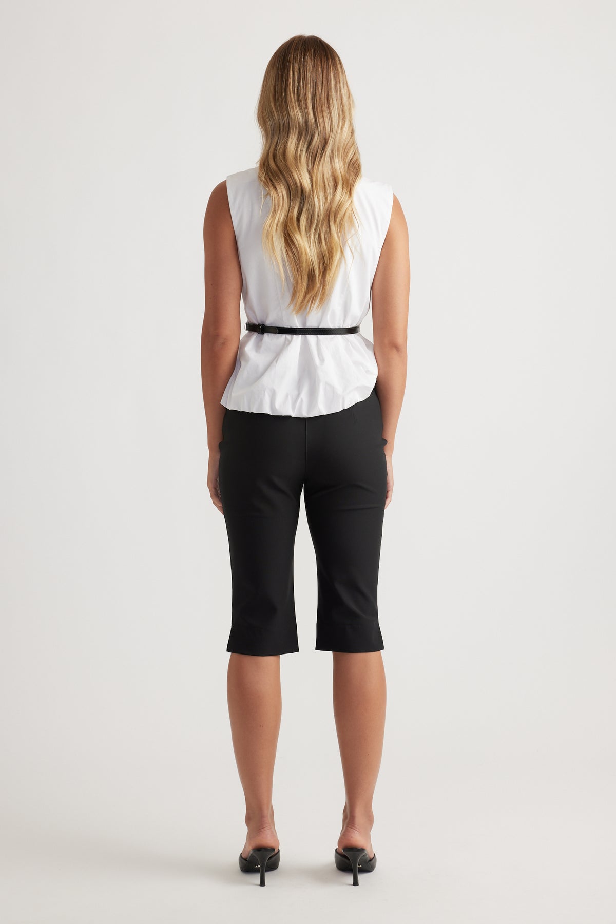 Woman seen from behind wearing Ava Belted Wrap Top in white with sleeveless design and black slim belt by DECJUBA