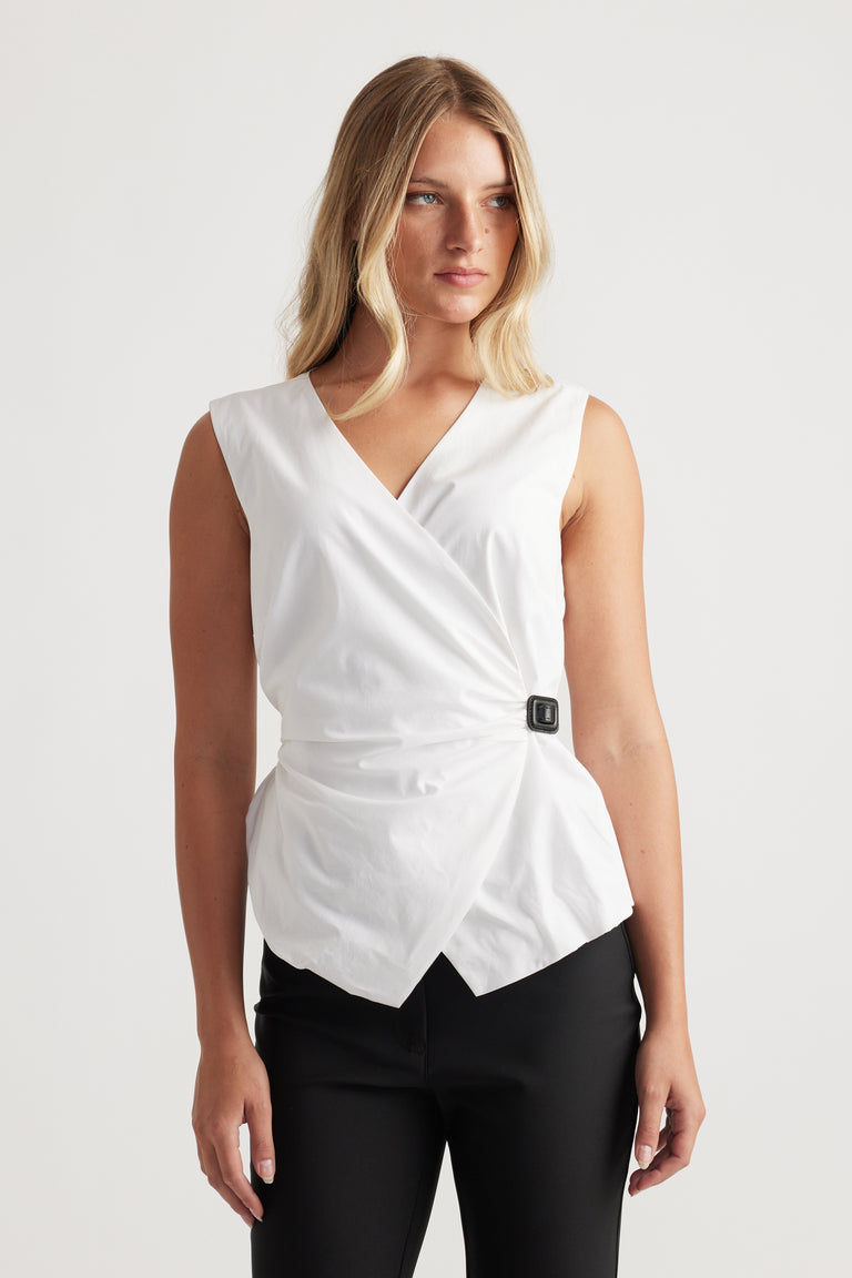 Woman wearing Ava Belted Wrap Top in white with sleeveless design and side buckle detail by DECJUBA