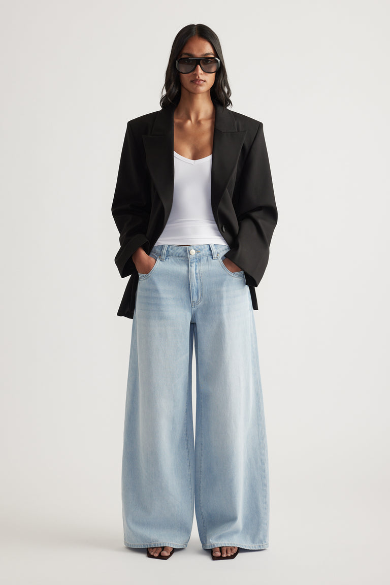 Woman wearing a black blazer with a white top and light blue super wide leg jeans