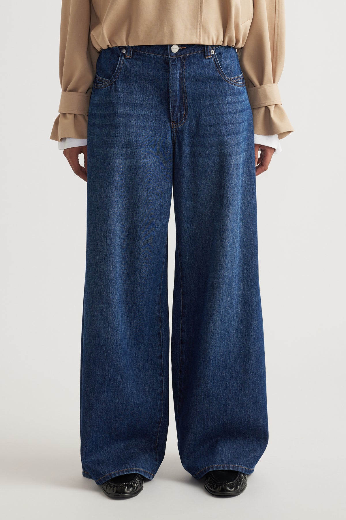 Dark blue wide-leg jeans styled with a beige blouse featuring cuffed balloon sleeves and black shoes