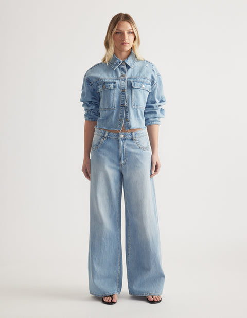 Woman wearing light blue wide-leg denim jeans paired with a cropped denim jacket and black sandals