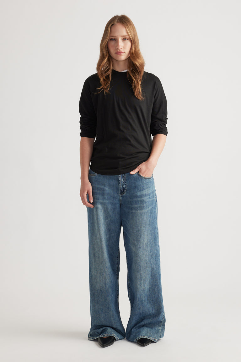 Woman wearing a fitted black long sleeve top styled with wide-leg faded blue denim jeans for a relaxed look