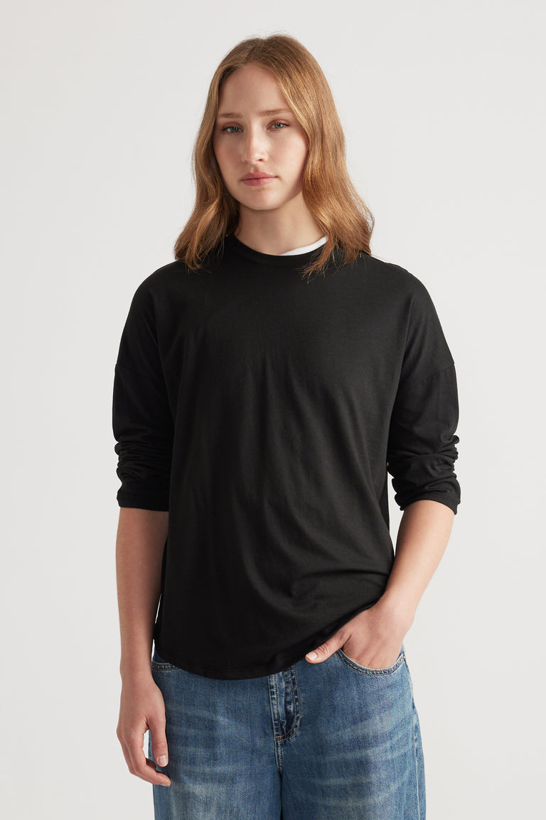 Woman wearing a fitted black long sleeve top paired with relaxed blue denim jeans for a minimalist casual look