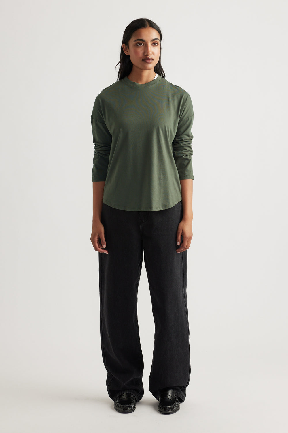 Woman wearing a relaxed fit fern green long sleeve top paired with wide-leg black pants and black shoes