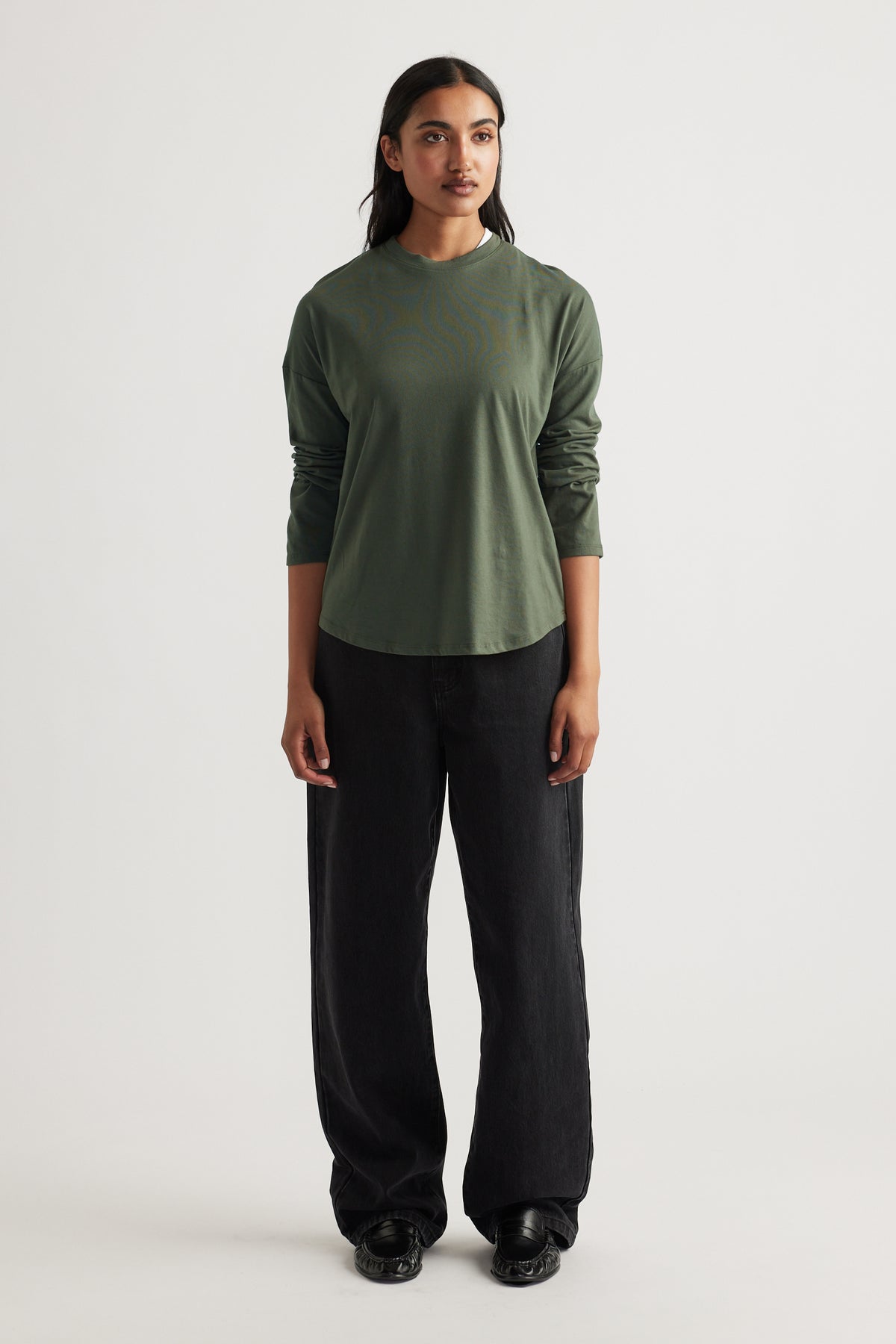 Woman wearing a relaxed fit fern green long sleeve top paired with wide-leg black pants and black shoes