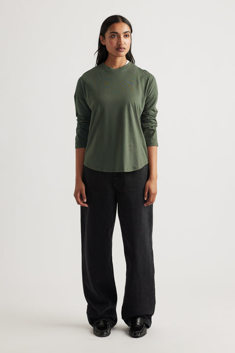 Woman wearing a relaxed fit fern green long sleeve top paired with wide-leg black pants and black shoes
