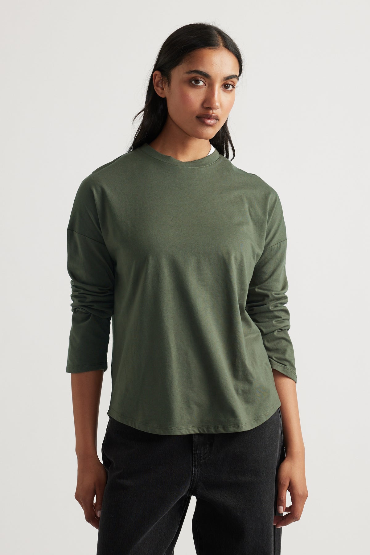 Woman wearing a relaxed fern green long sleeve top paired with black casual pants for a simple, stylish look