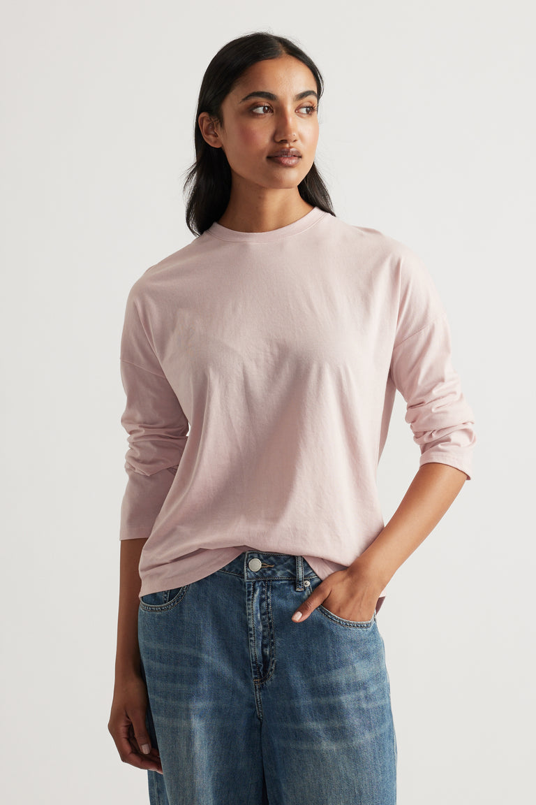 Woman wearing a soft pink long sleeve top paired with relaxed blue denim jeans for a casual, effortless look