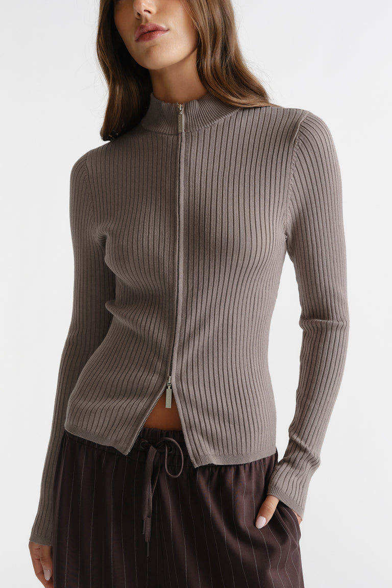 Woman wearing a dune-toned D-Luxe Knit Zip Long Sleeve with a fine ribbed texture and zip-up collar detail