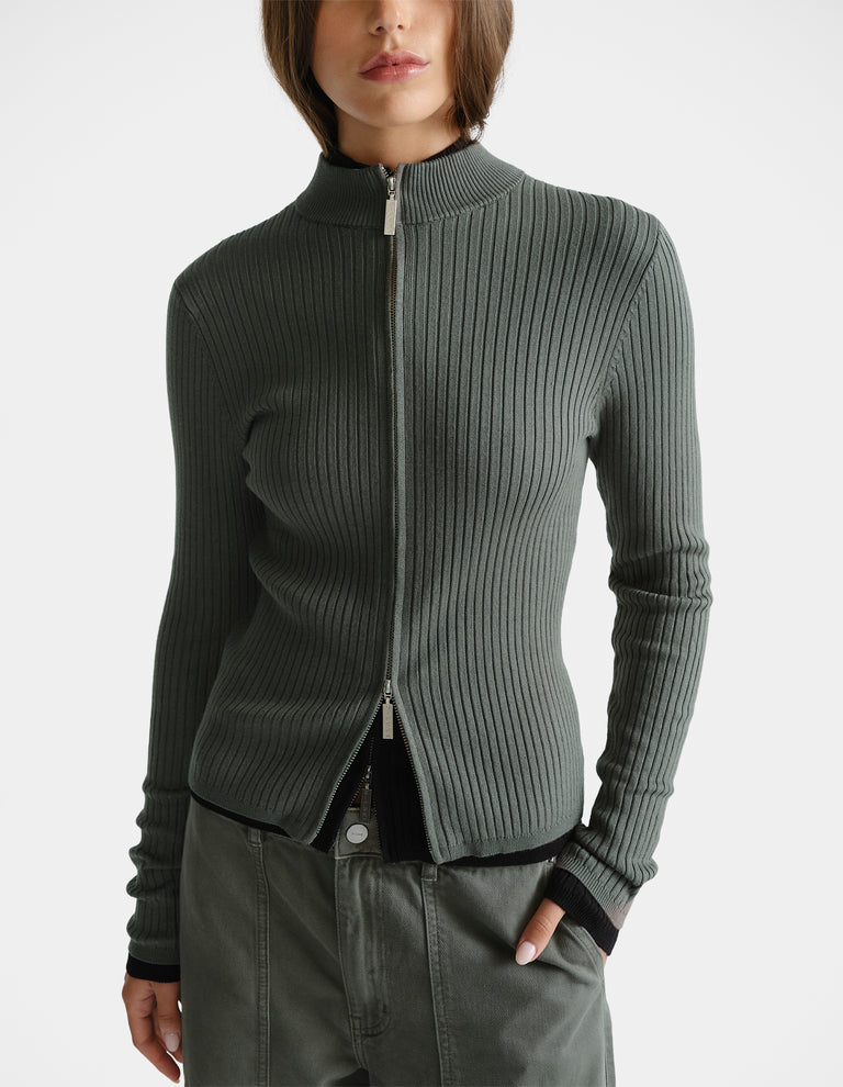 Woman wearing a thyme green D-Luxe Knit Zip Long Sleeve with ribbed texture and a sleek high collar for a modern look