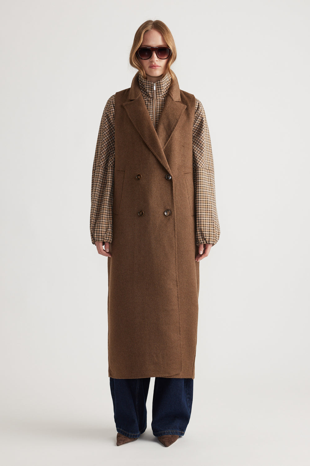 Model wearing Lucia Felled Two Piece Coat in warm brown layered over a checked shirt with wide-leg jeans and sunglasses