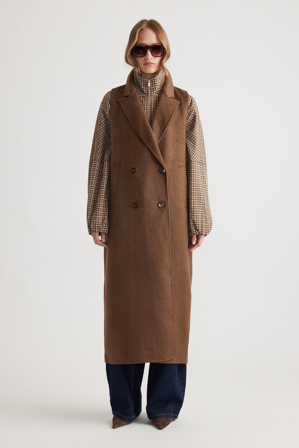 Model wearing Lucia Felled Two Piece Coat in warm brown layered over a checked shirt with wide-leg jeans and sunglasses