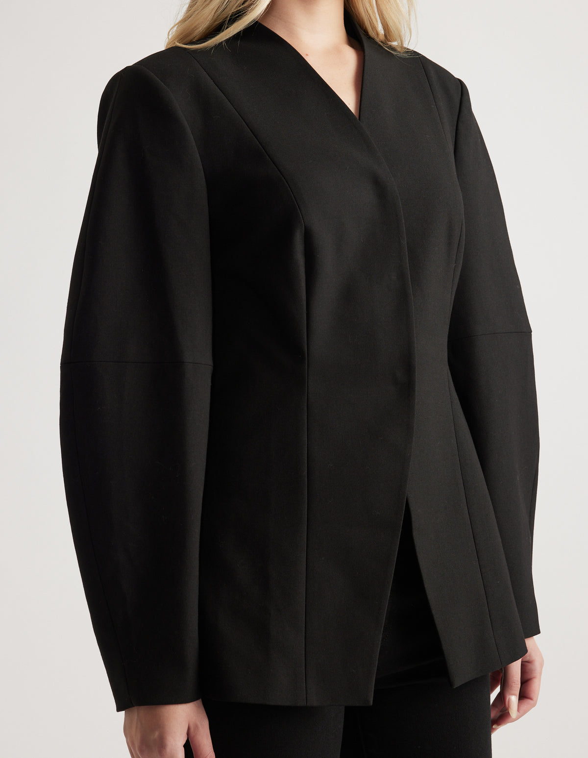 Woman wearing a tailored black blazer with long barrel sleeves and a grown-on collar, styled for versatile wear