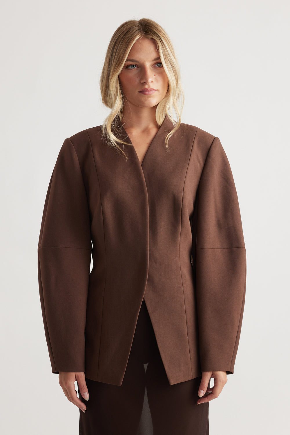 Woman wearing the Ruby Barrel Sleeve Blazer in rich coffee brown with structured shoulders for a bold, modern look by DECJUBA