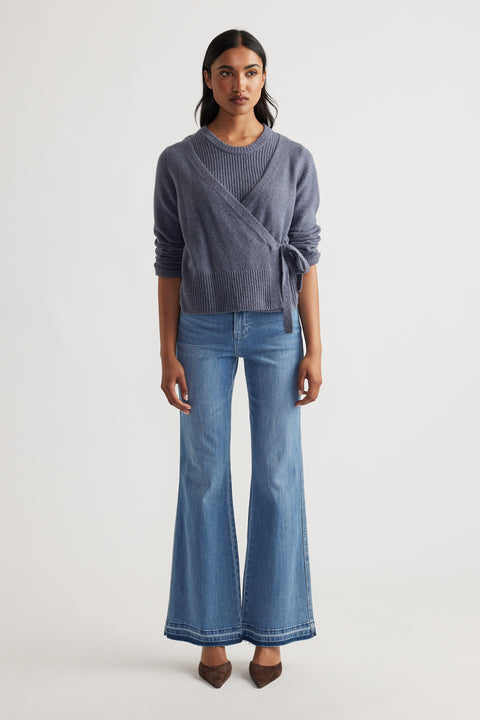 Woman wearing Tamica Layered Jumper in soft shadow blue layered over knit top, styled with flared denim jeans and pointed shoes