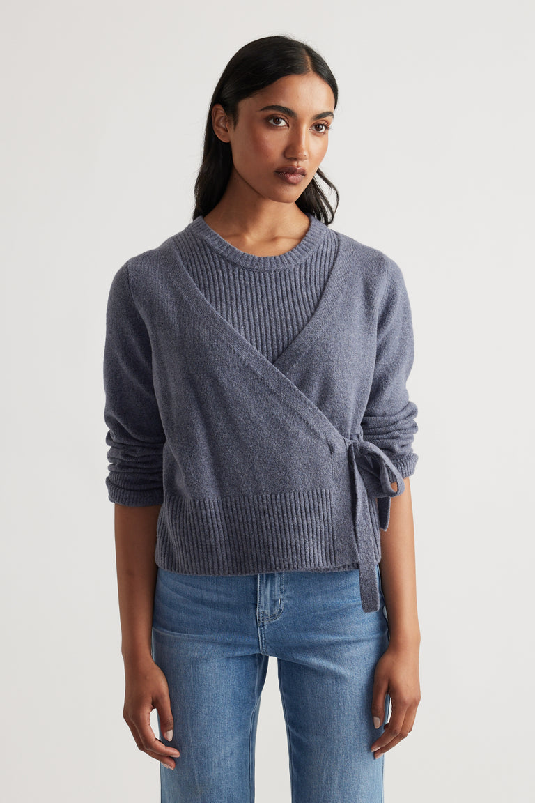 Woman wearing Tamica Layered Jumper in soft shadow blue with a wrap tie side and ribbed detailing by DECJUBA.