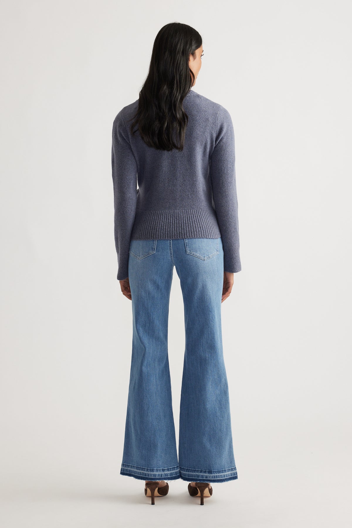 Woman wearing Tamica Layered Jumper in soft blue knit paired with high-waisted flared jeans and heeled sandals by DECJUBA