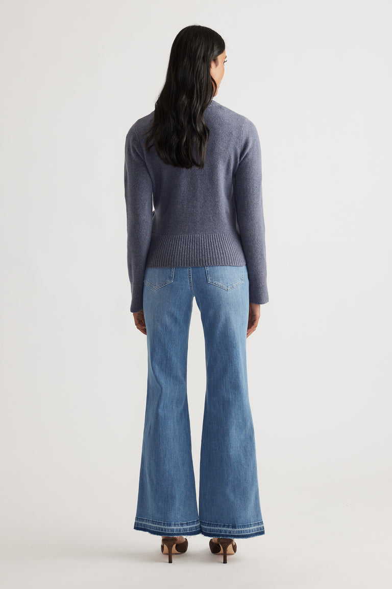 Woman wearing Tamica Layered Jumper in soft blue knit paired with high-waisted flared jeans and heeled sandals by DECJUBA