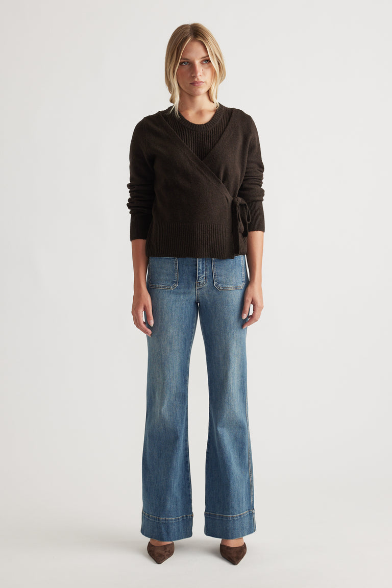 Woman wearing Tamica Layered Jumper in rich brown with wrap detail, paired with light wash wide-leg jeans and pointed shoes
