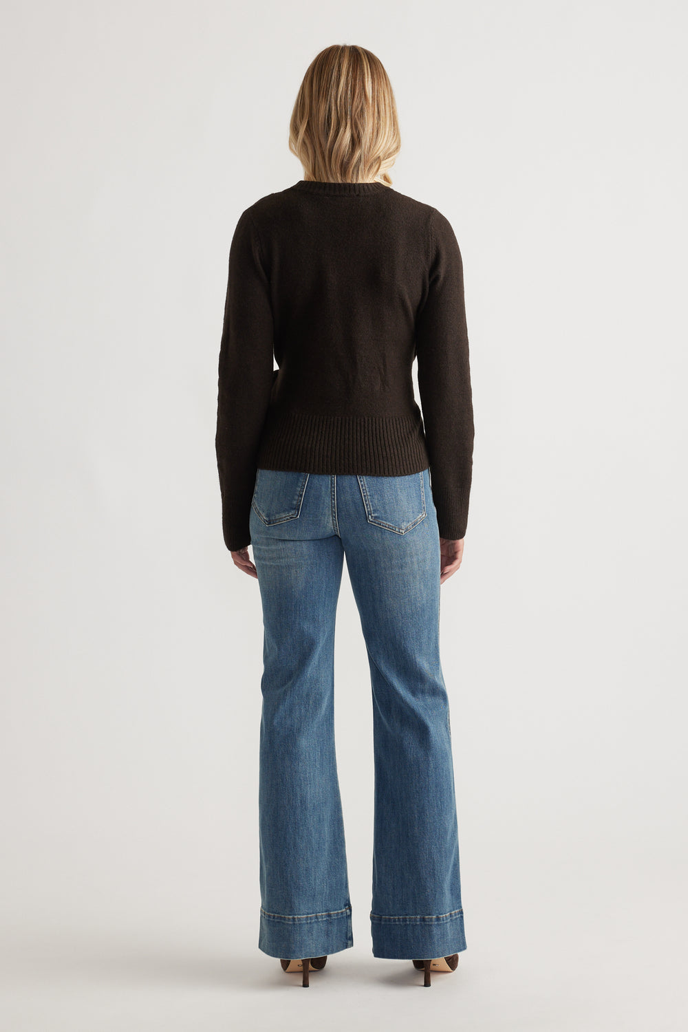 Back view of Tamica Layered Jumper in rich brown knit paired with classic blue wide-leg denim jeans and neutral heels.