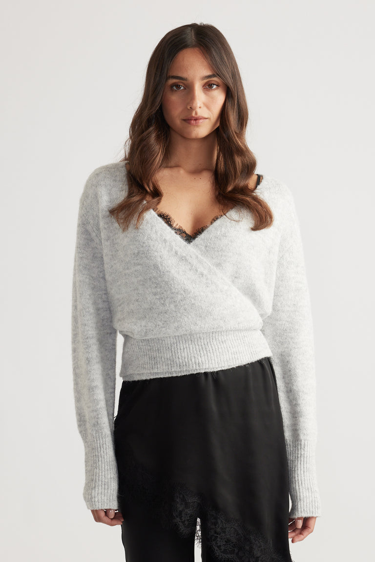 Soft light grey crossover knit sweater with a ribbed hem paired with a black lace-trimmed satin skirt