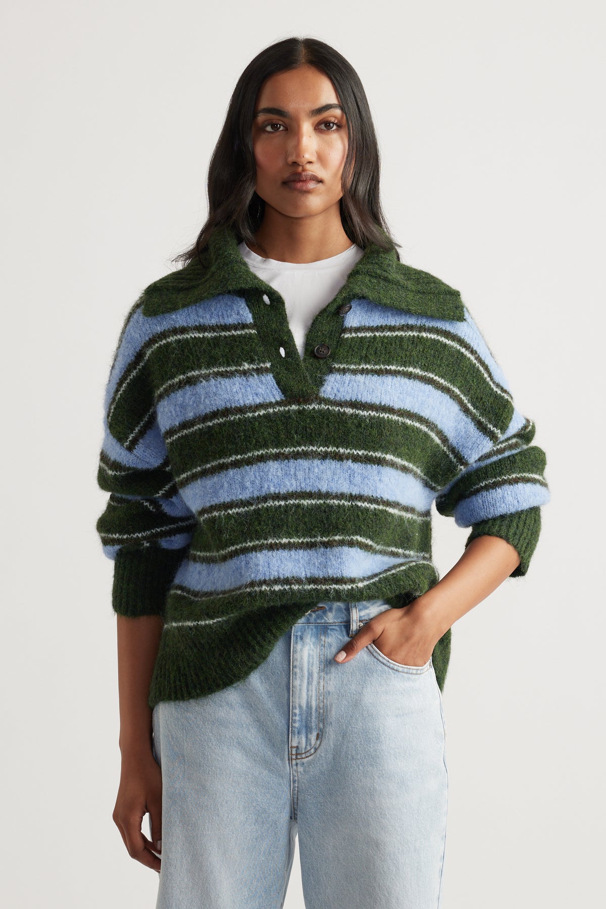 Woman wearing a soft striped knit polo in green and blue, styled casually with light wash high-rise jeans.