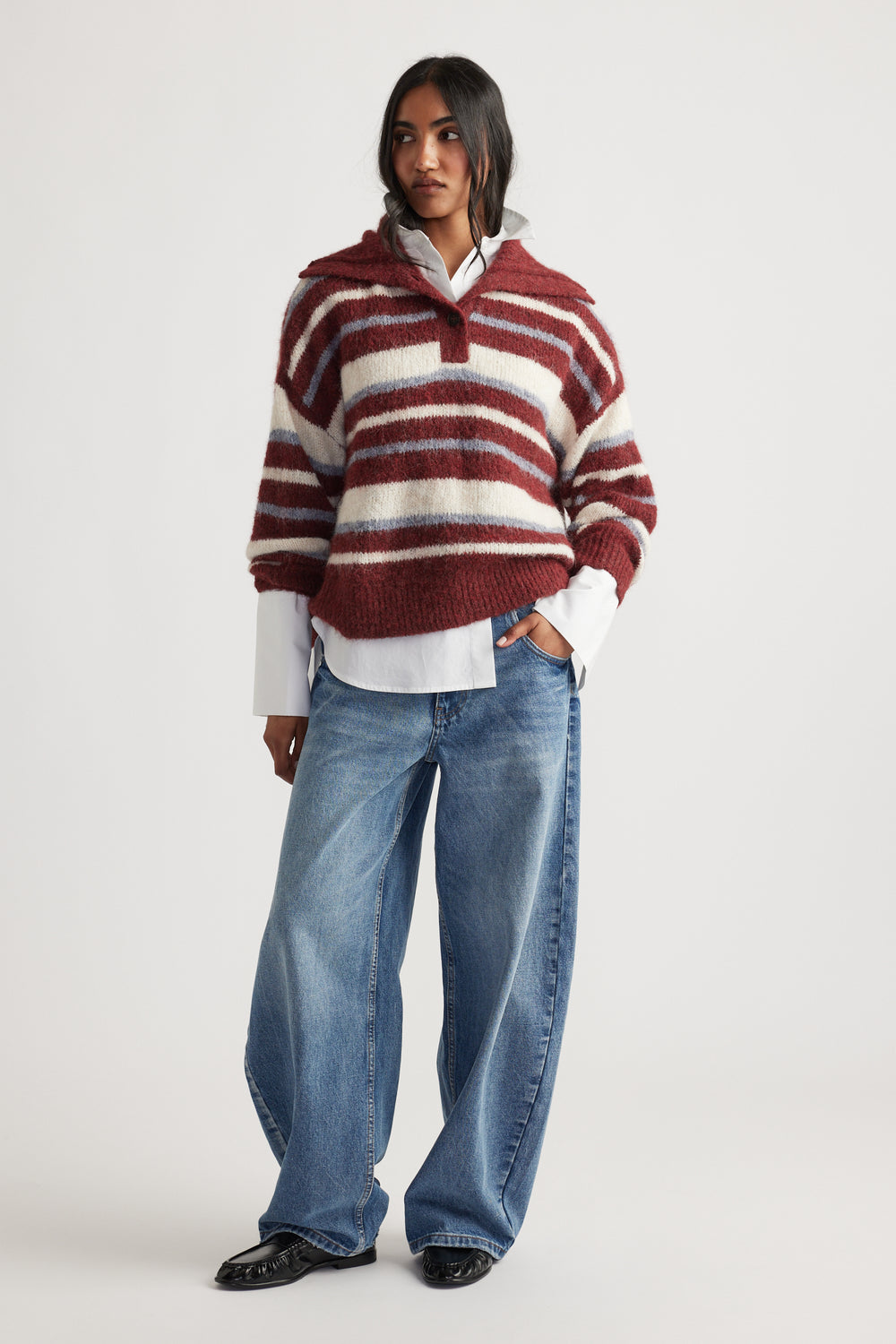 Woman wearing Riley Knit Polo with bold red and cream stripes layered over white shirt and relaxed denim jeans by DECJUBA Australian brand