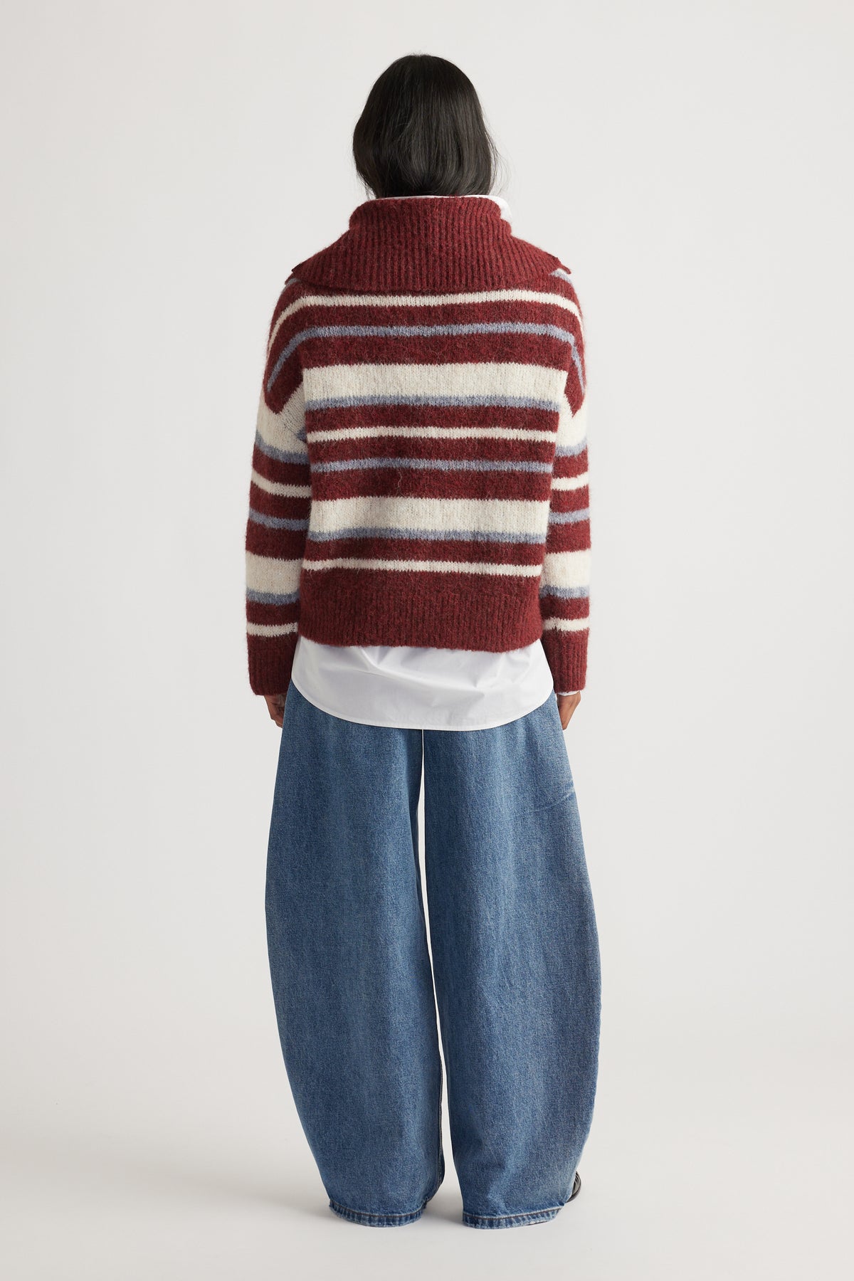 Back view of woman wearing Riley Knit Polo in maroon and cream stripes layered over white shirt with wide-leg denim jeans by DECJUBA Australian brand