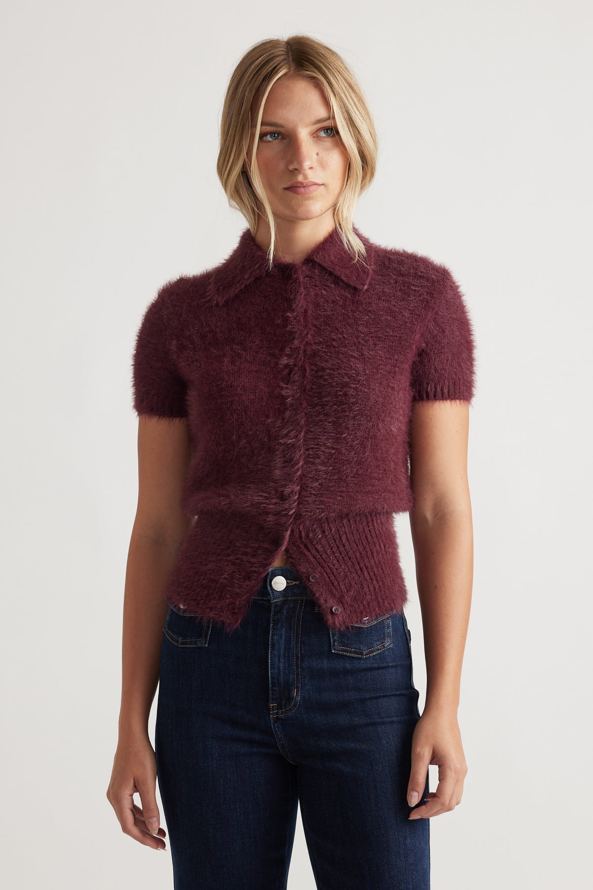 Woman wearing a plum Rosie Fluffy Knit Polo Tee with a soft textured finish styled with dark blue jeans by DECJUBA