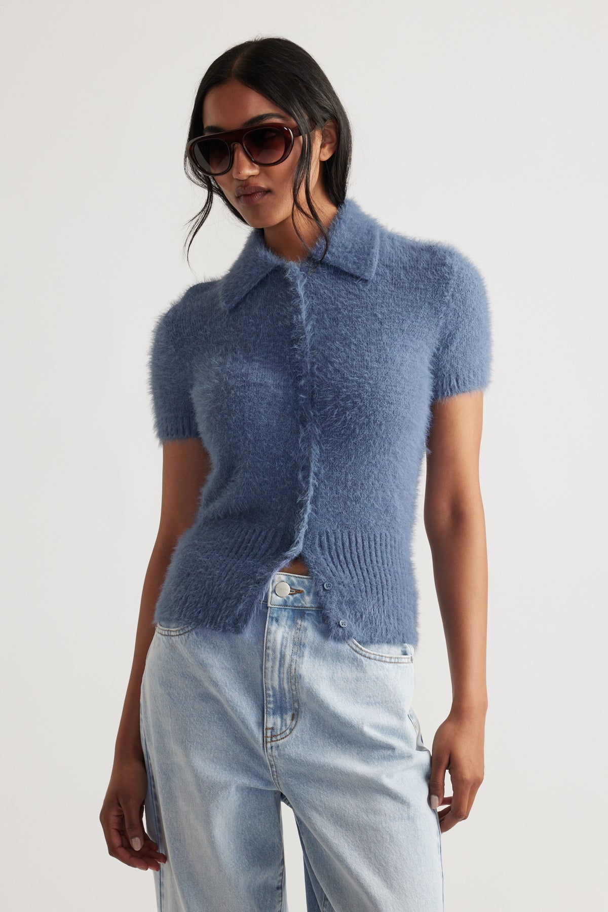 Woman wearing Rosie Fluffy Knit Polo Tee in soft steel blue paired with light wash denim jeans for a casual look by DECJUBA