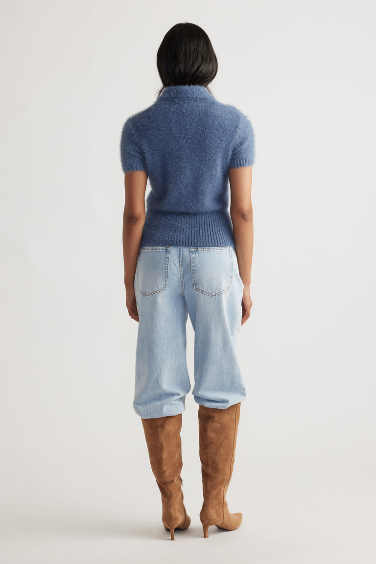 Back view of woman wearing steel blue Rosie Fluffy Knit Polo Tee paired with relaxed light denim jeans and tan suede boots