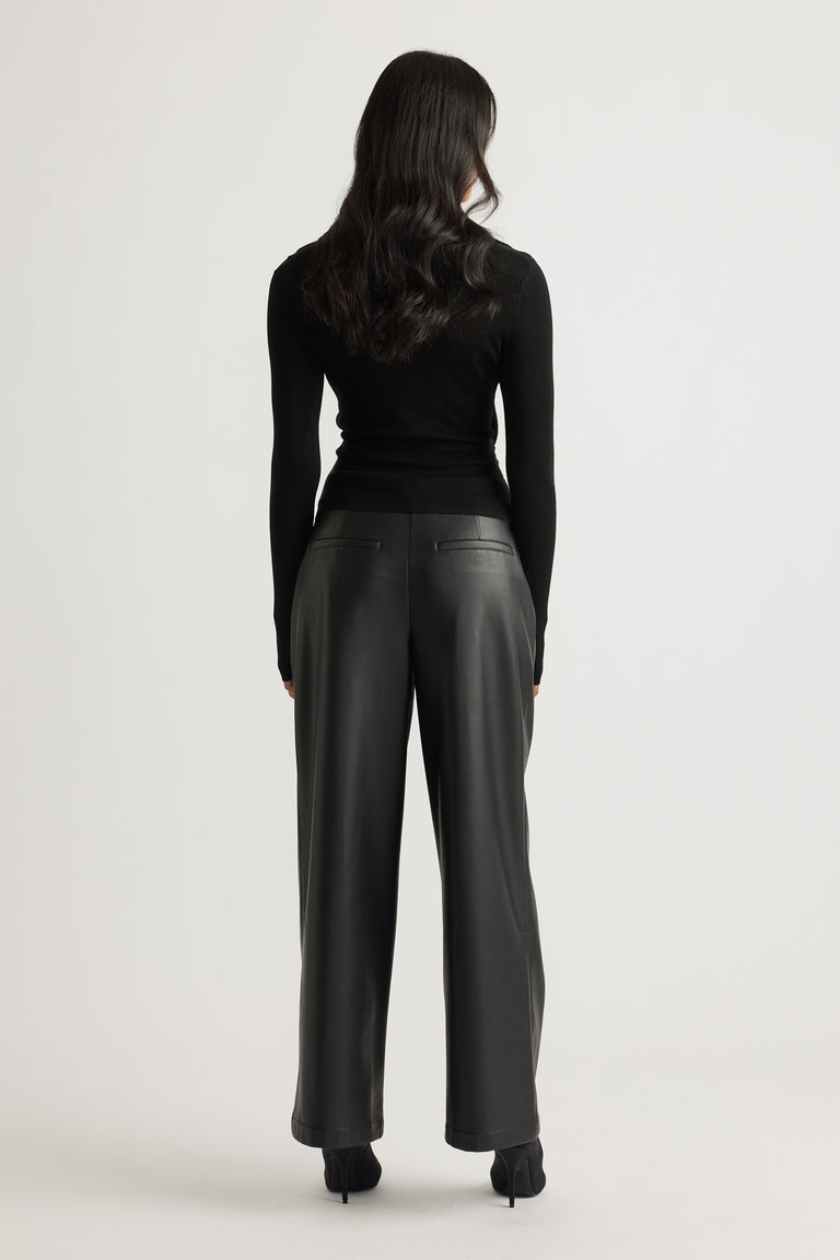 Woman wearing a fitted black knit top with long sleeves paired with high-waisted wide-leg black leather pants