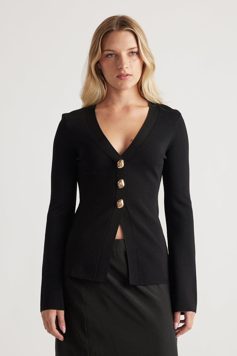 Woman wearing a fitted black longline cardigan with gold buttons, featuring a deep V-neck and long sleeves