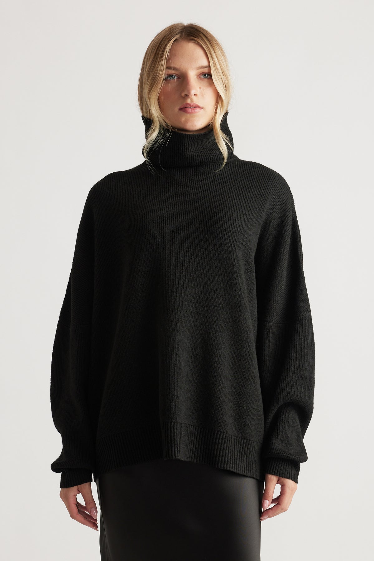 Black knit jumper with a relaxed fit and high roll neck, styled for comfort and everyday versatility