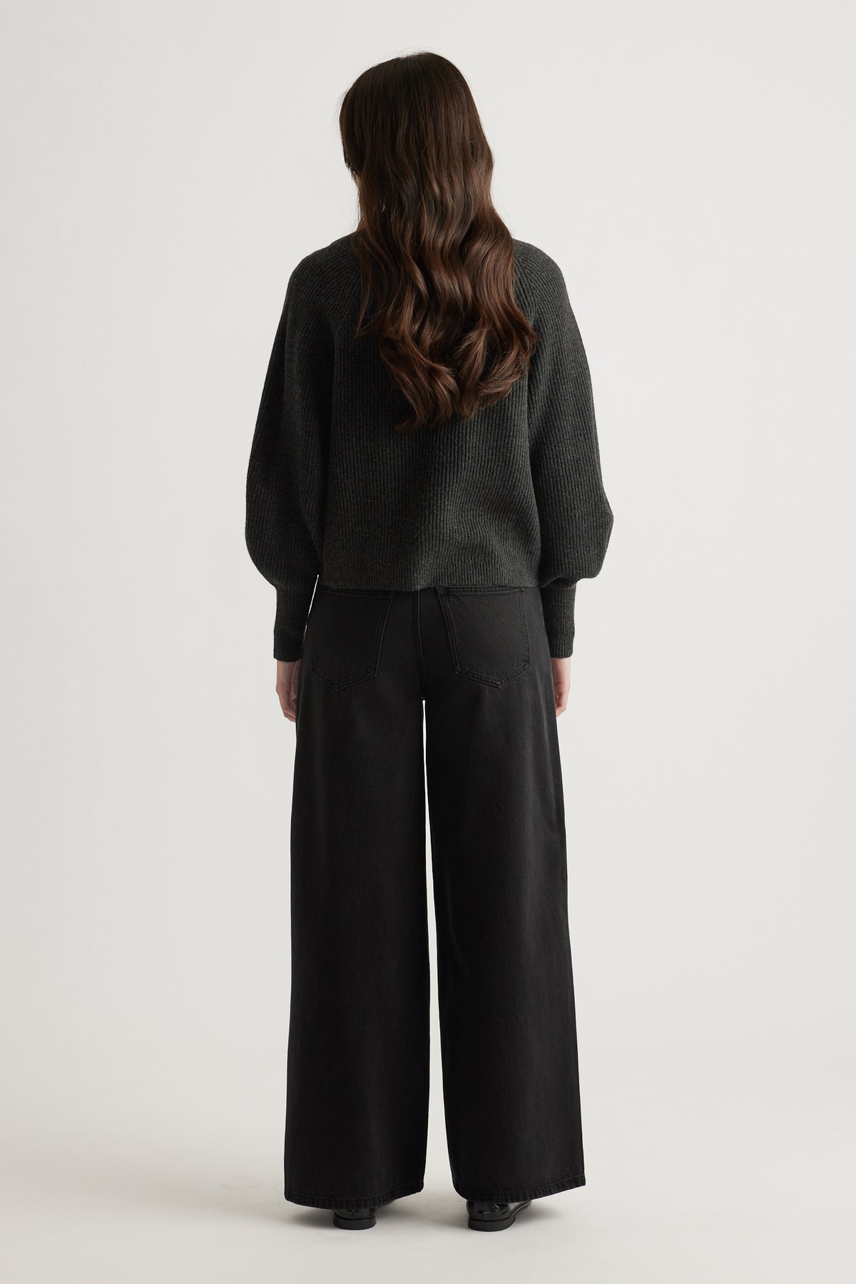 Woman wearing a charcoal knit cardigan with balloon sleeves styled with wide-leg black pants for a relaxed look